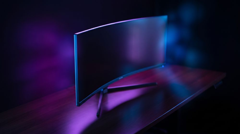 Monitor ultrawide curvo com iluminação RGB roxa e azul, estilo Nerdesk